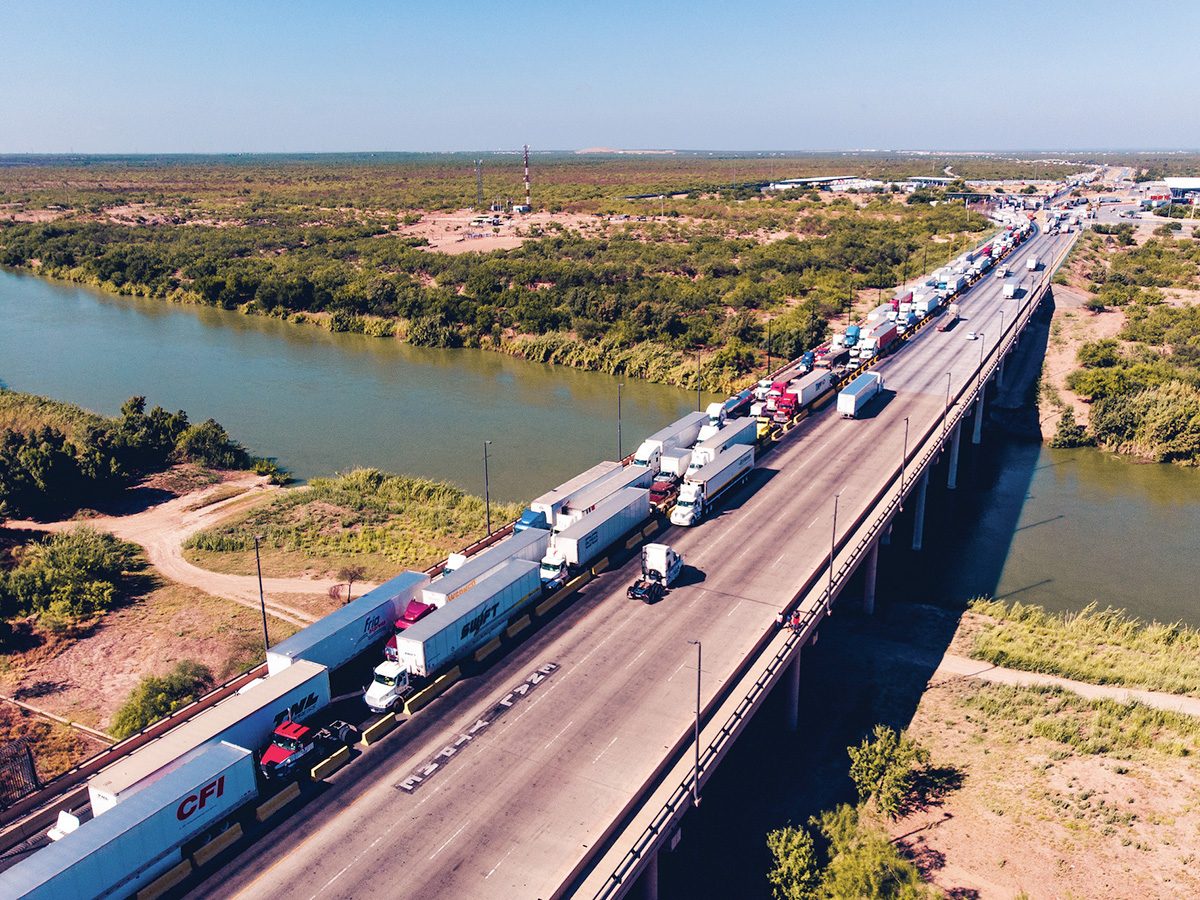 Aerial view of trucks crossing the international bridge along the USMCA corridor